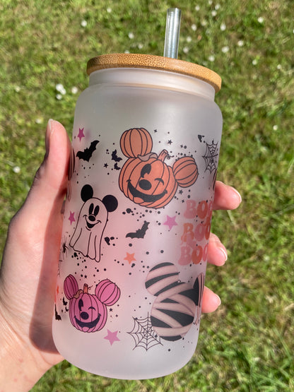 Frosted tumbler with Halloween-themed designs held in a hand against a grassy background