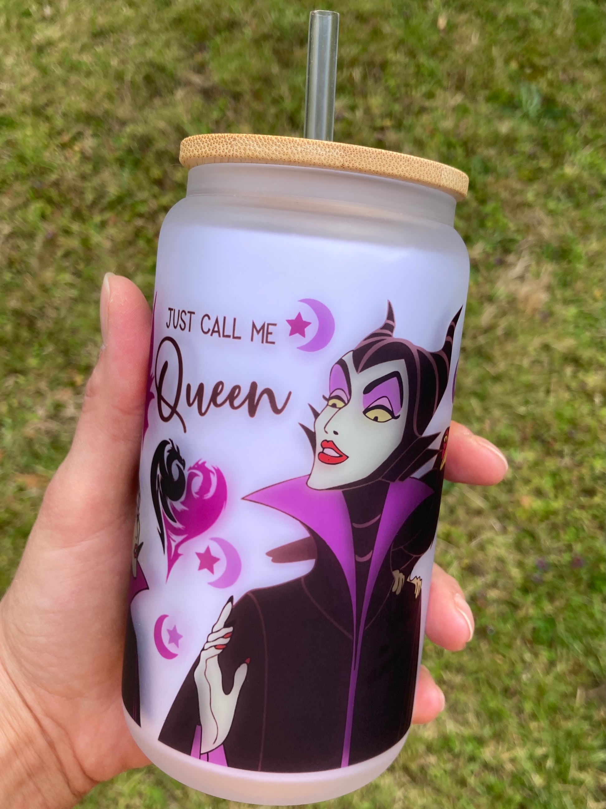 Tumbler with a character design and text 'Just call me Queen' held in a hand against a grass background