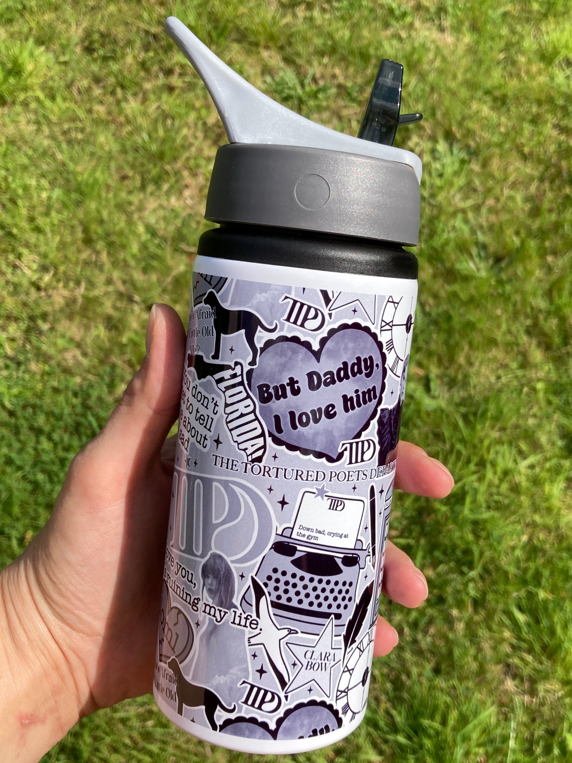 Person holding a water bottle with text and graphics against a grassy background