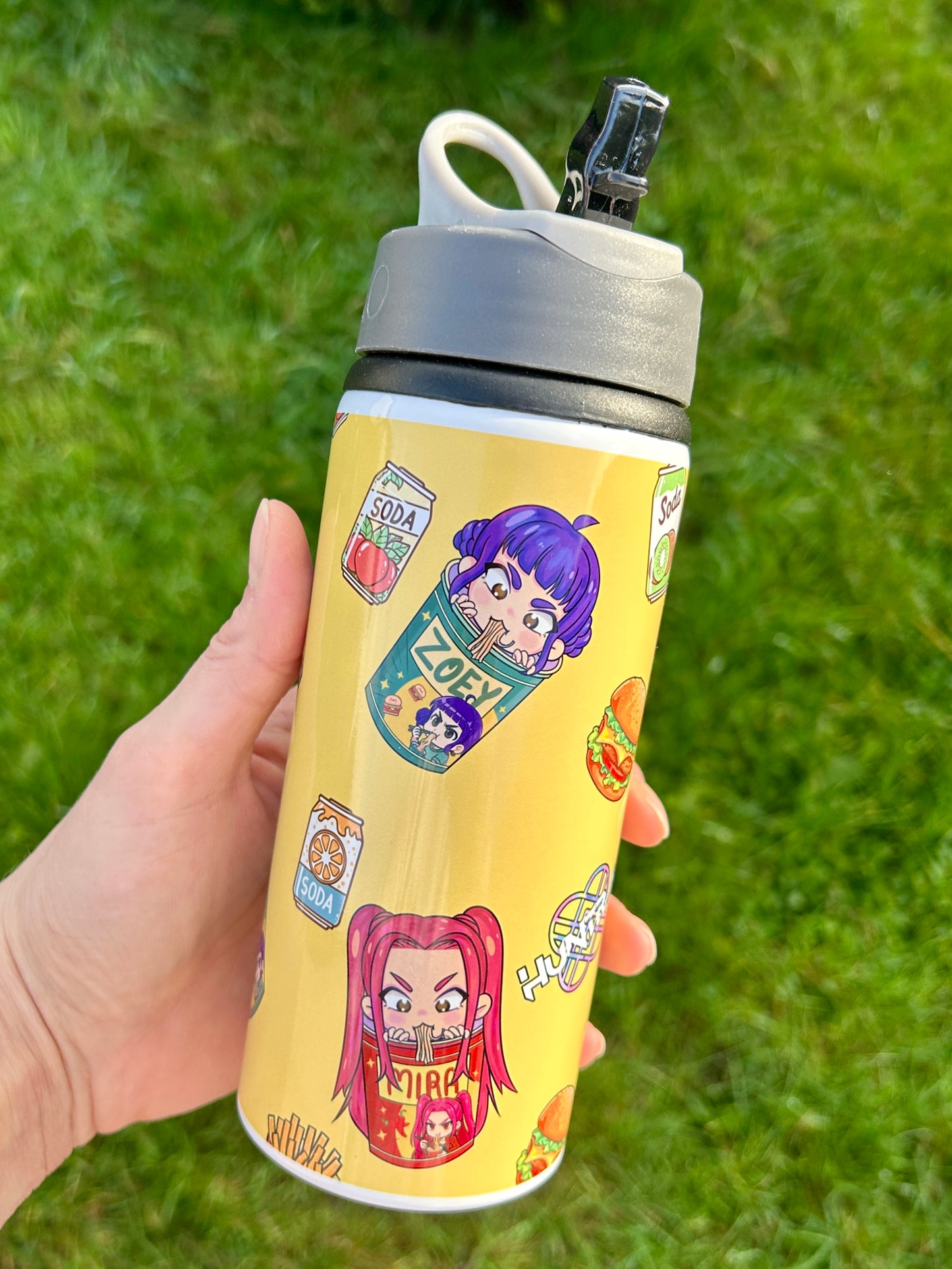 Yellow water bottle with character stickers held against a grass background